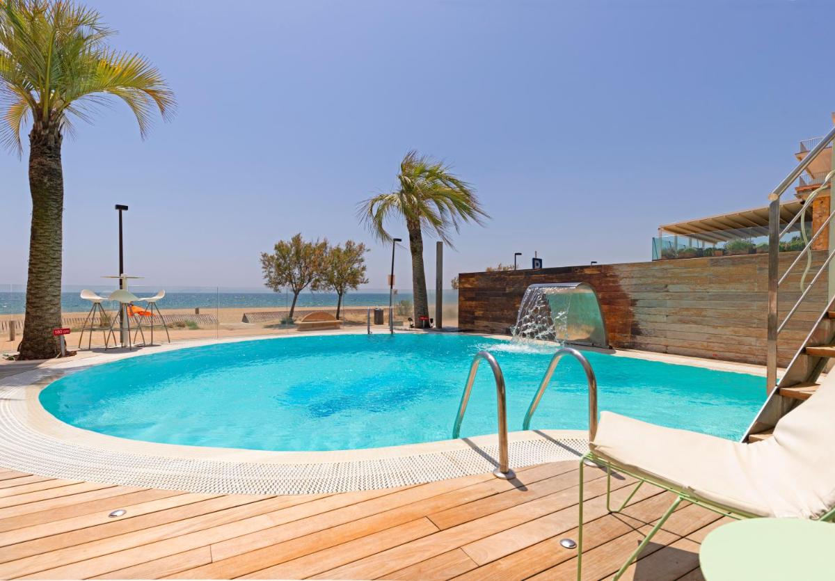 una piscina con una silla, palmeras y la playa en Hotel Maritim 4 Superior, en Roses