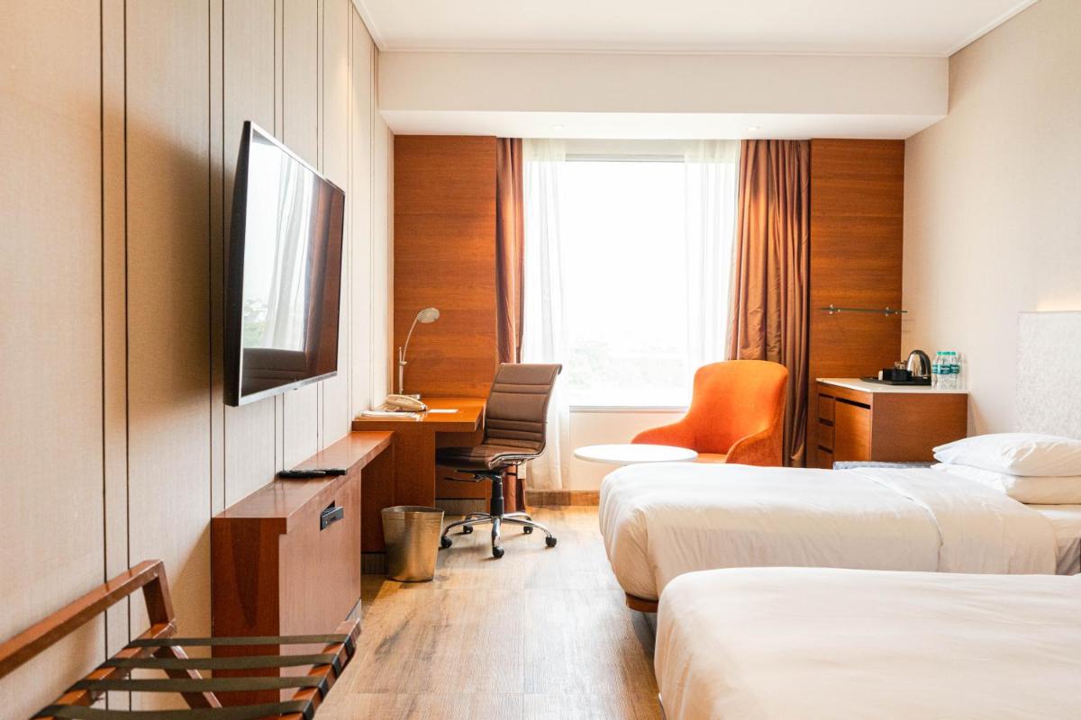 a hotel room with two beds and a desk and a television at Hyatt Centric Janakpuri New Delhi in New Delhi