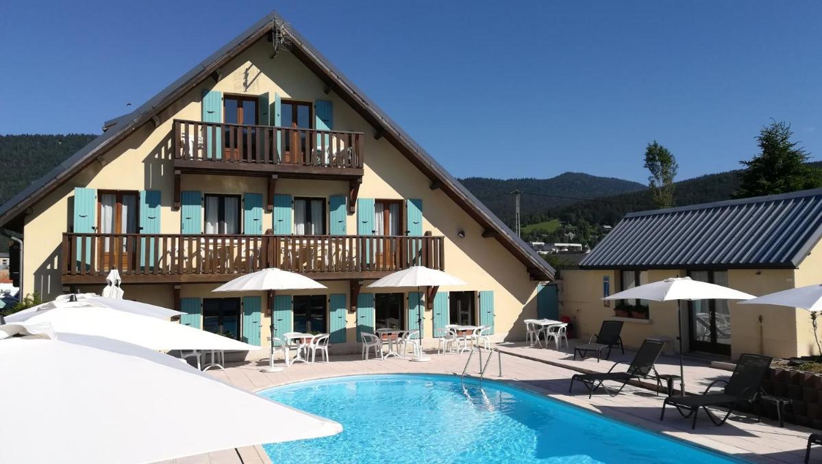 un hôtel avec une piscine devant un immeuble dans l'établissement Hôtel Restaurant Les Tilleuls, à Autrans