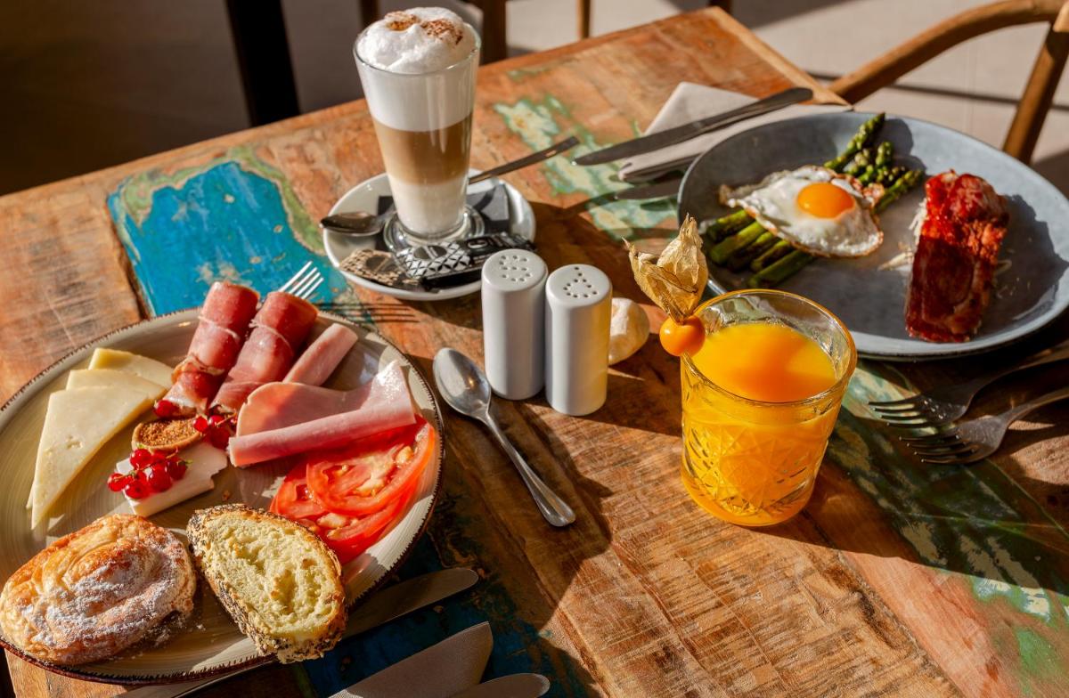 una mesa con dos platos de desayuno y una bebida en Marins Beach Club - Adults Only Hotel, en Cala Millor