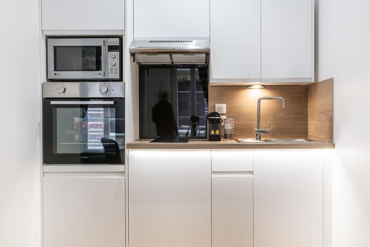 une cuisine blanche avec un évier et un micro-ondes dans l'établissement TOWNHOUSE TROUVILLE - Appart'Hotel & Studios, à Trouville-sur-Mer