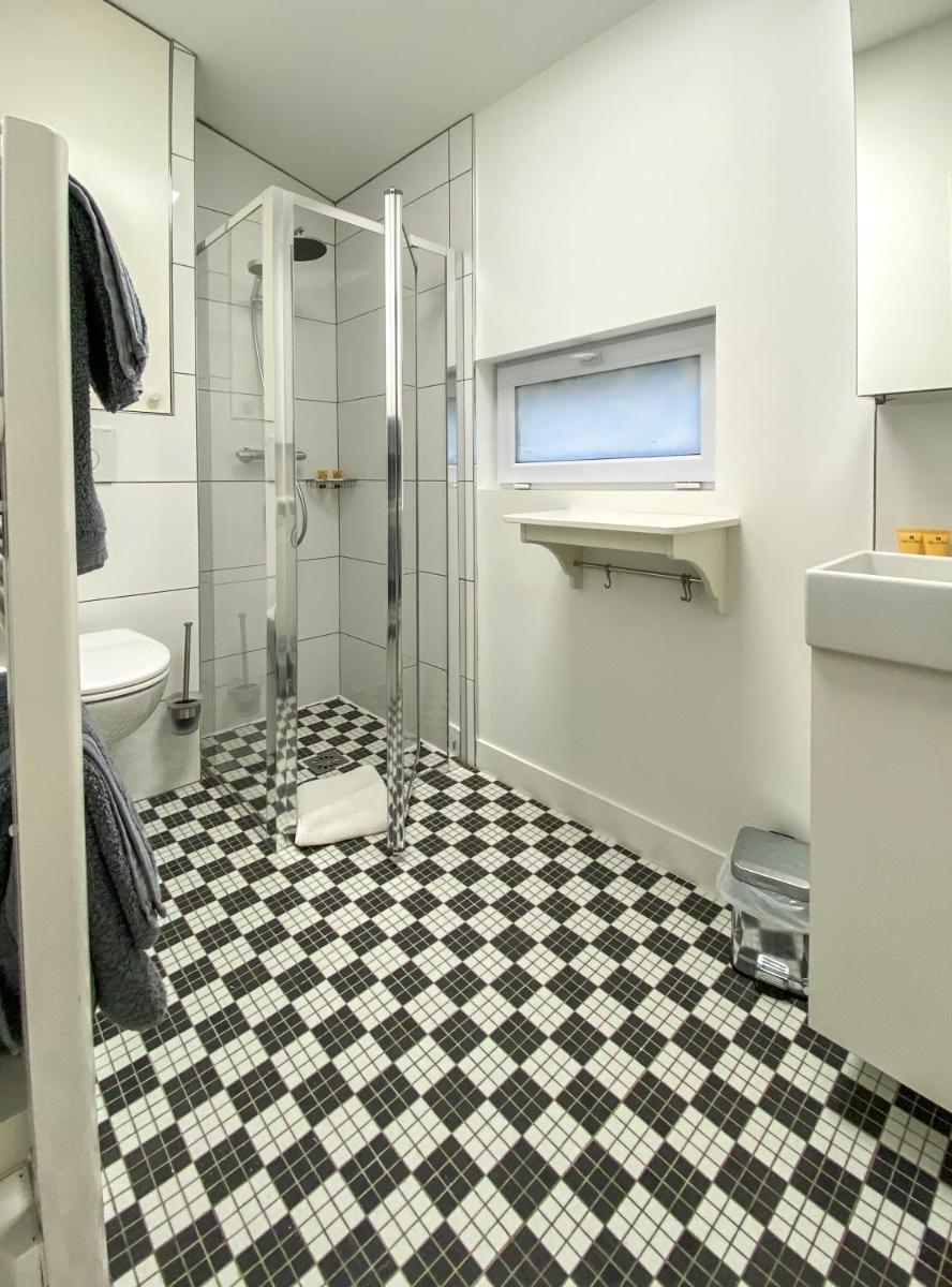 La salle de bains est pourvue d'une douche et d'un sol en damier noir et blanc. dans l'établissement TOWNHOUSE TROUVILLE - Appart'Hotel & Studios, à Trouville-sur-Mer