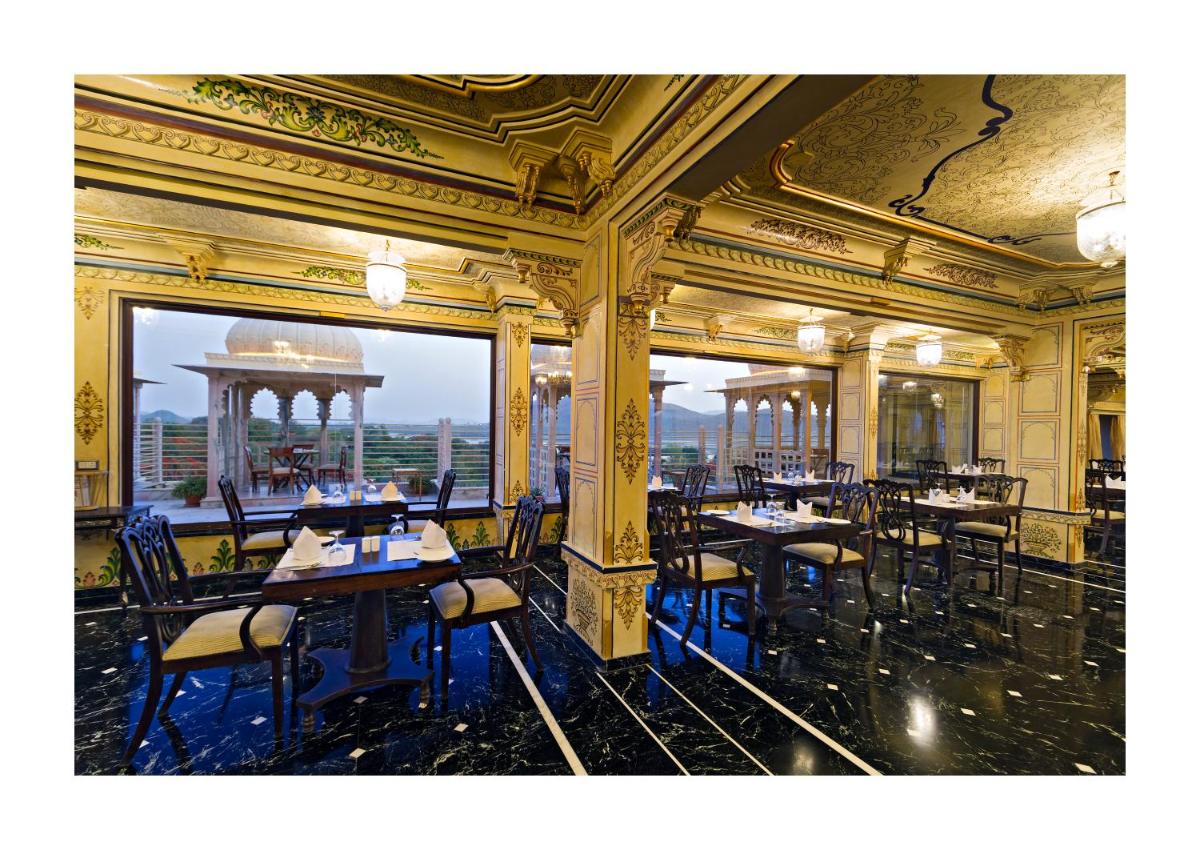 a restaurant with tables and chairs in a building at Chunda Palace in Udaipur