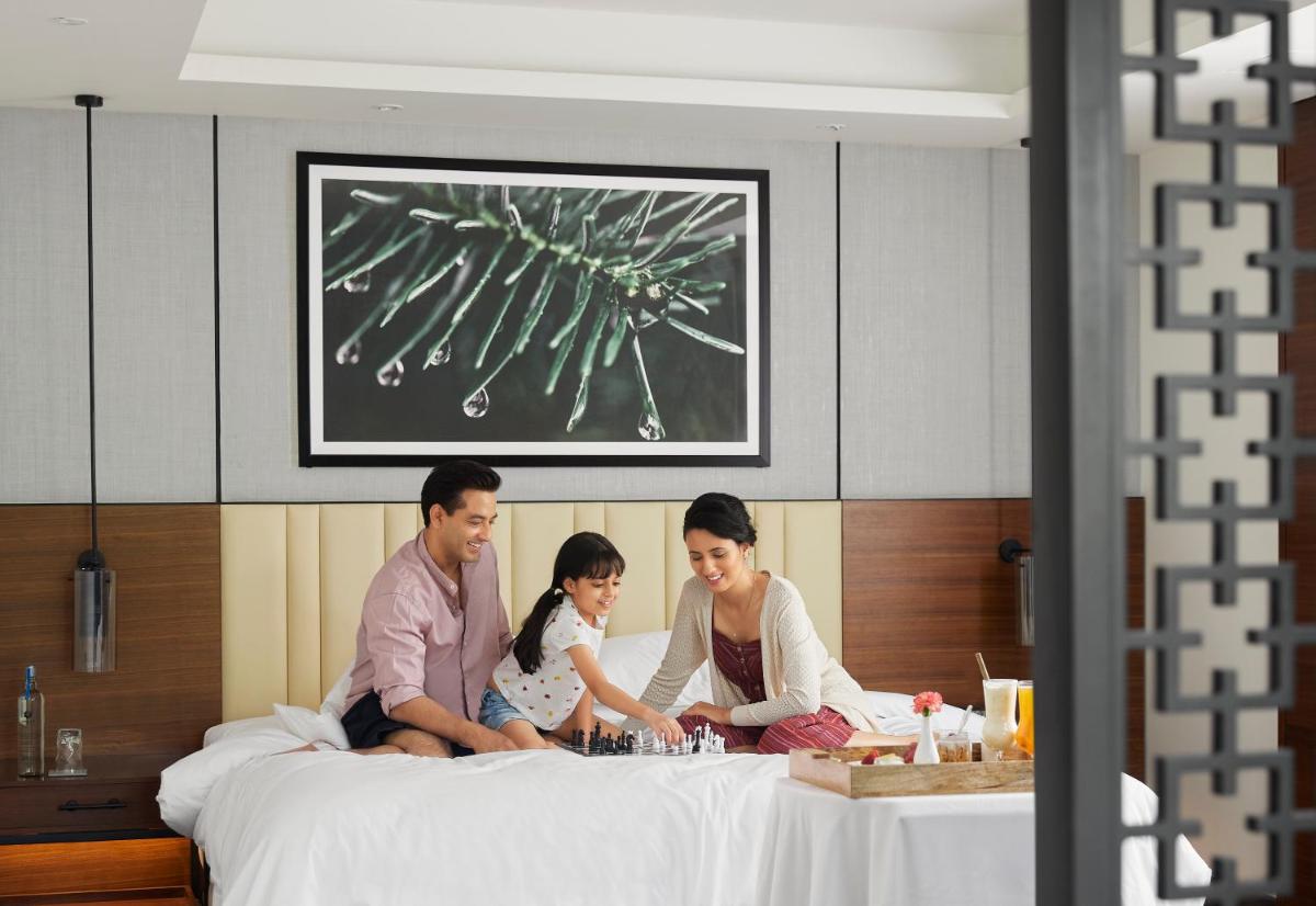 a family sitting on top of a bed at Hyatt Regency Dehradun Resort and Spa in Dehradun