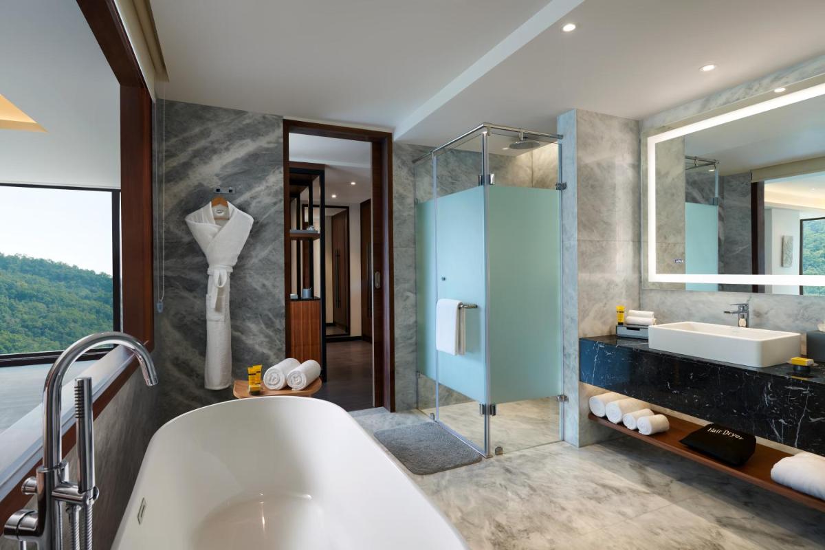 a bathroom with a tub and a sink and a mirror at Hyatt Regency Dehradun Resort and Spa in Dehradun