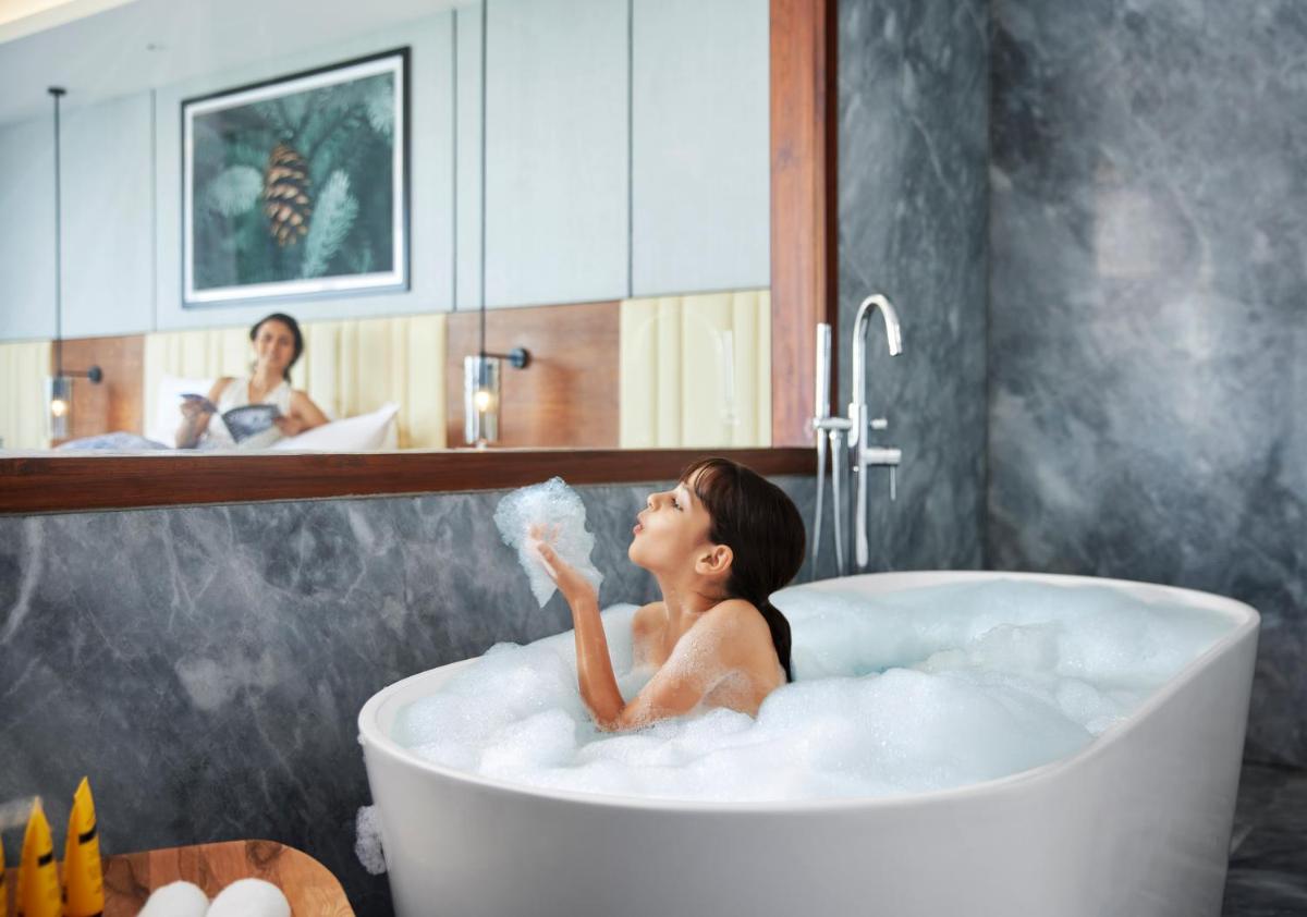 a woman sitting in a bath tub with a bubblegum at Hyatt Regency Dehradun Resort and Spa in Dehradun