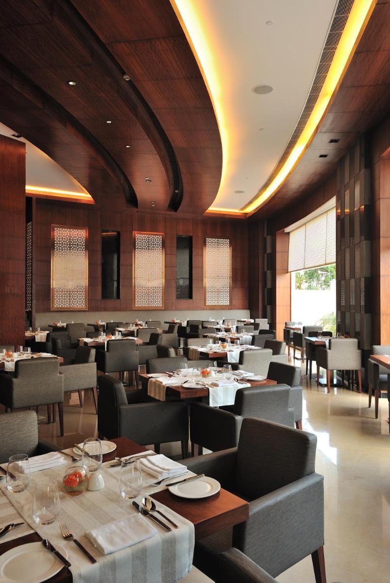 a dining room with tables and chairs in a restaurant at The Anya Hotel-Golf Course Road in Gurgaon