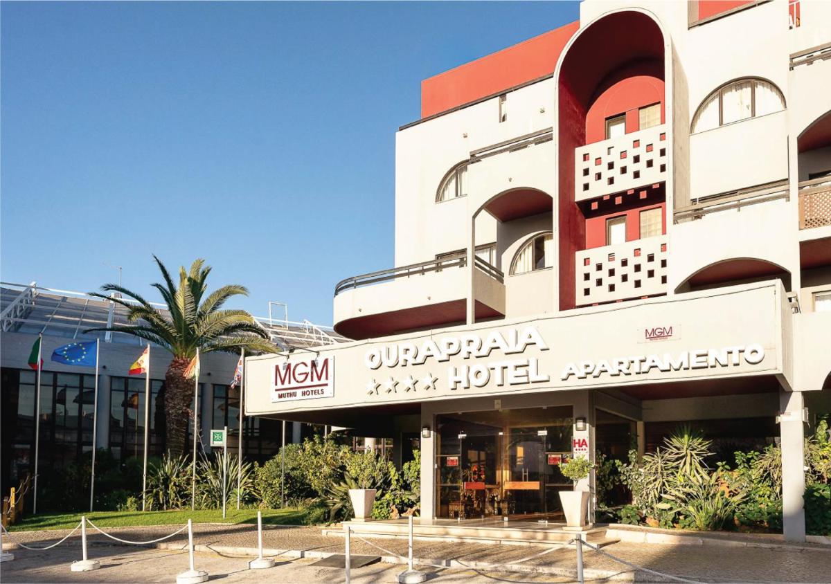 um prédio com uma palmeira na frente em Muthu Oura Praia Hotel em Albufeira