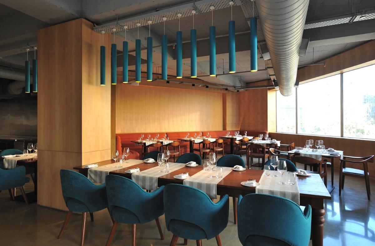 a dining room with tables and blue chairs at The Anya Hotel-Golf Course Road in Gurgaon