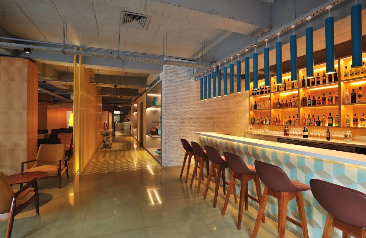 a bar with brown chairs and a counter with bottles at The Anya Hotel-Golf Course Road in Gurgaon
