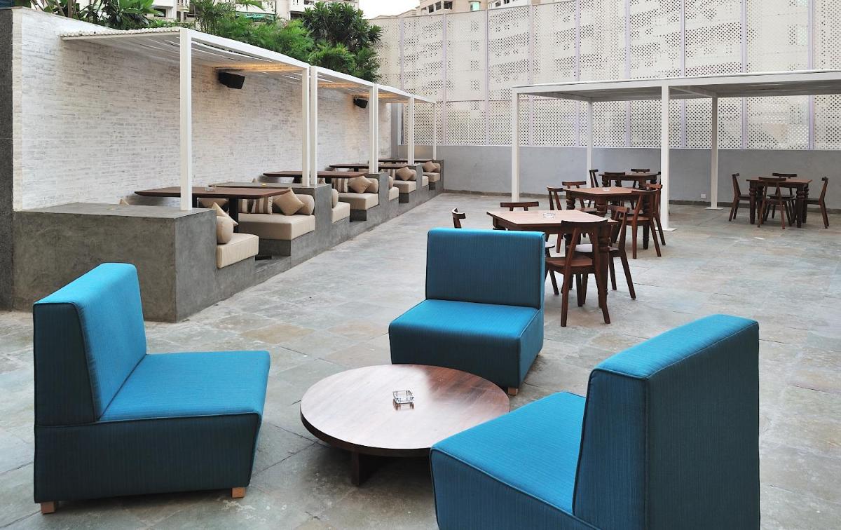 a restaurant with blue chairs and tables and tables at The Anya Hotel-Golf Course Road in Gurgaon