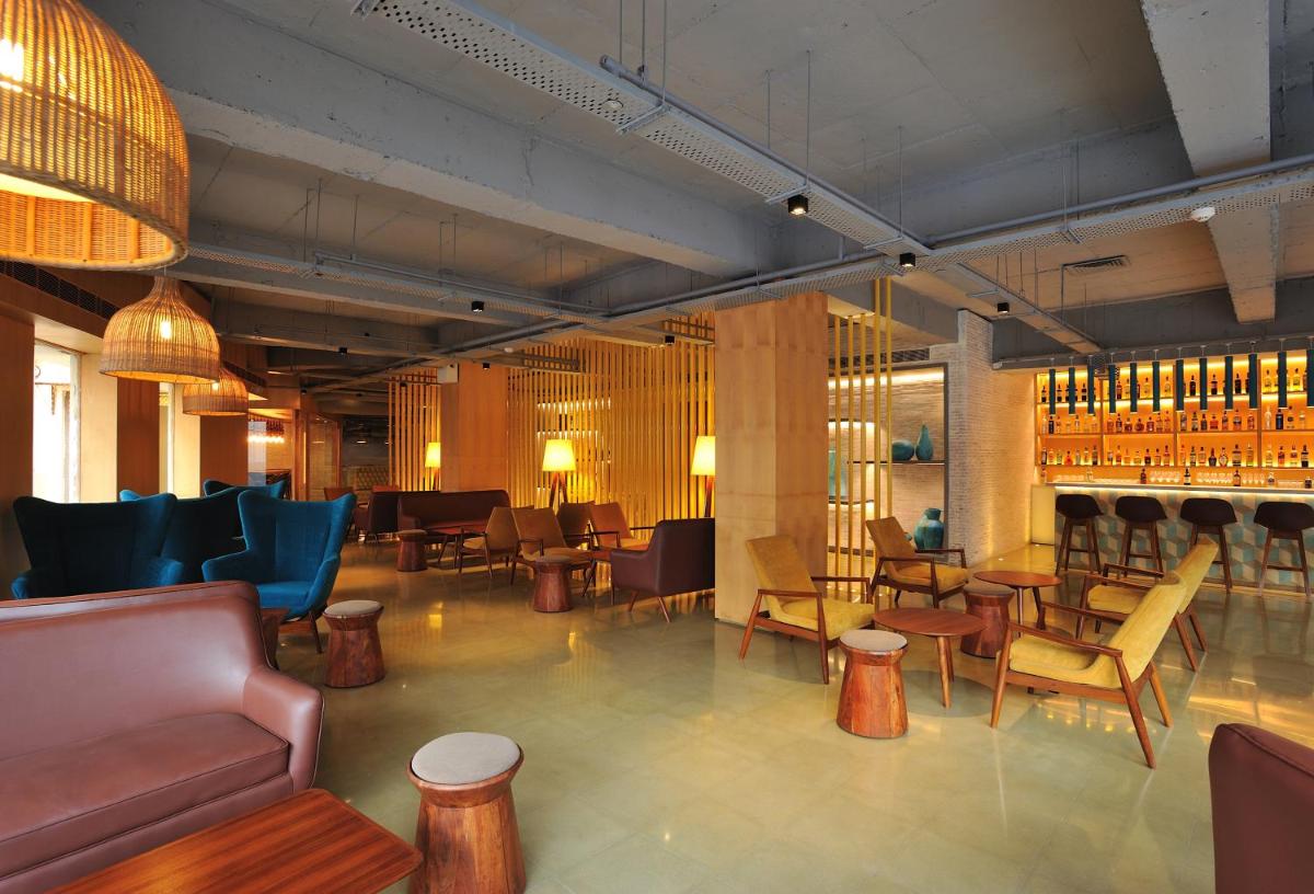 a restaurant with a bar with chairs and tables at The Anya Hotel-Golf Course Road in Gurgaon