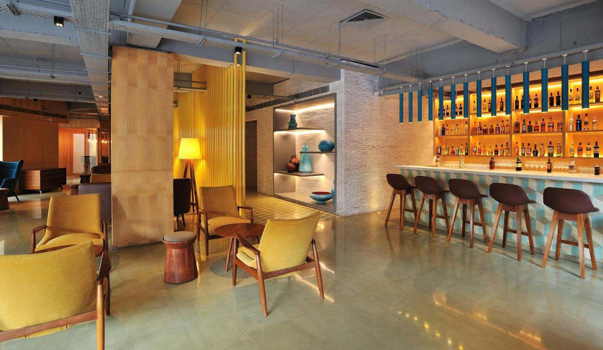 a bar in a restaurant with yellow chairs and tables at The Anya Hotel-Golf Course Road in Gurgaon