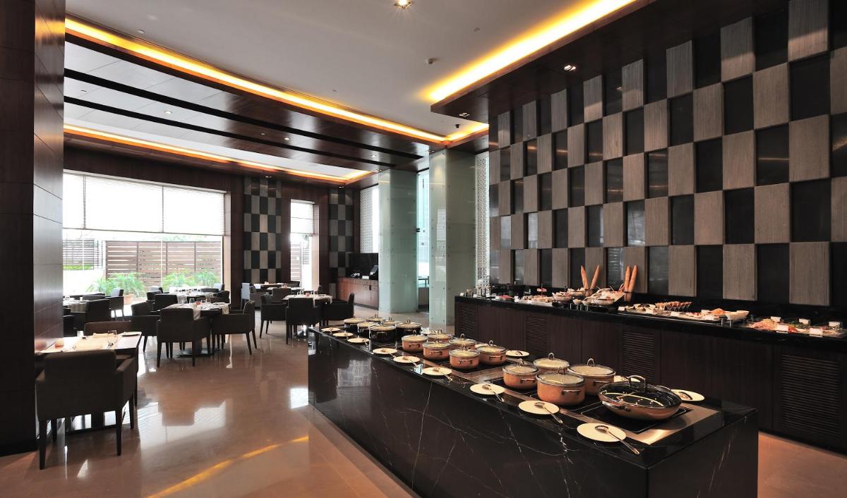 a restaurant with a buffet line with tables and chairs at The Anya Hotel-Golf Course Road in Gurgaon