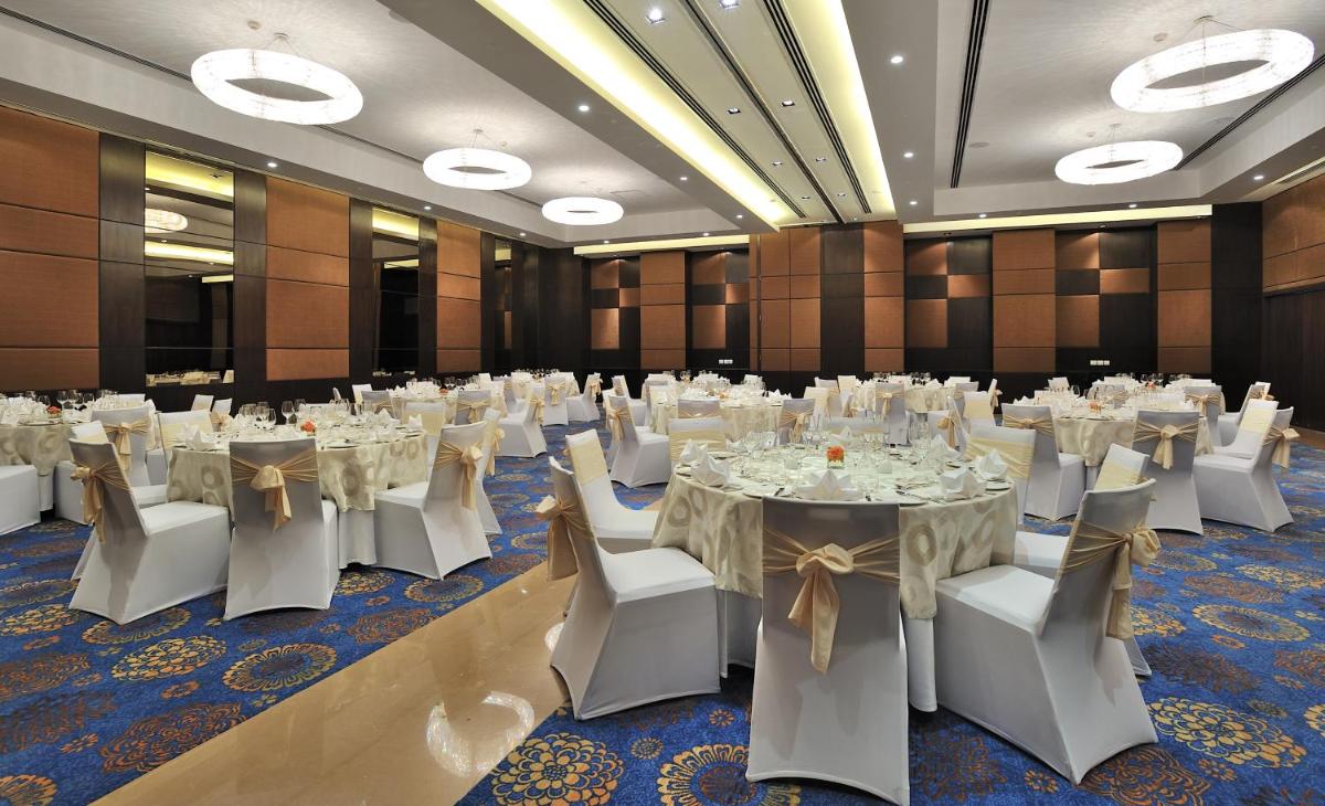 a banquet hall with white tables and white chairs at The Anya Hotel-Golf Course Road in Gurgaon
