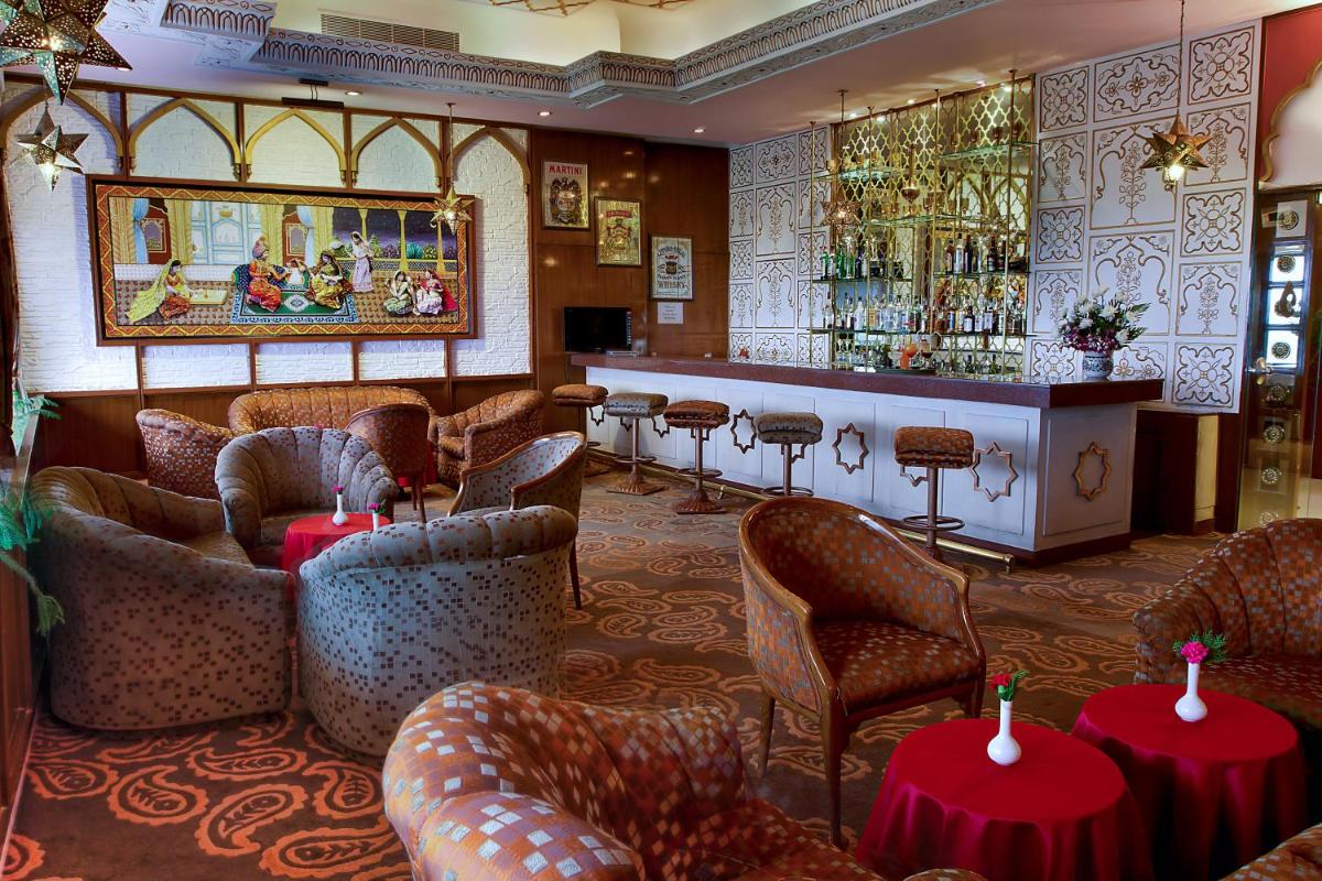 a restaurant with a bar with tables and chairs at Hotel Clarks Shiraz in Agra
