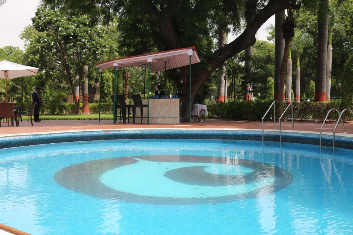 a large blue swimming pool in a park at Hotel Clarks Shiraz in Agra