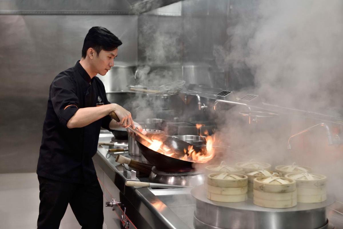 a man cooking food in a pan on a stove at Four Seasons Hotel Bengaluru at Embassy ONE in Bengaluru a man cooking food in a pan on a stove at Four Seasons Hotel Bengaluru at Embassy ONE in Bengaluru