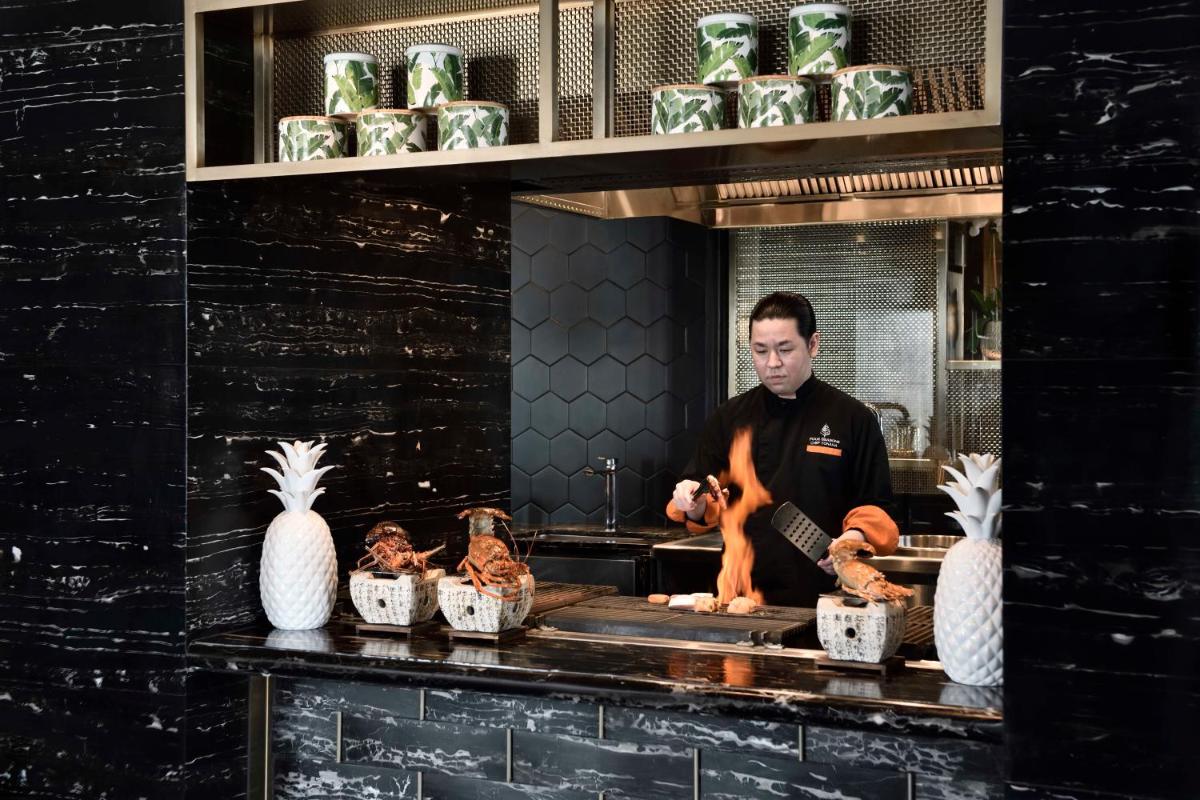a man preparing food in a kitchen with chickens at Four Seasons Hotel Bengaluru at Embassy ONE in Bengaluru a man preparing food in a kitchen with chickens at Four Seasons Hotel Bengaluru at Embassy ONE in Bengaluru