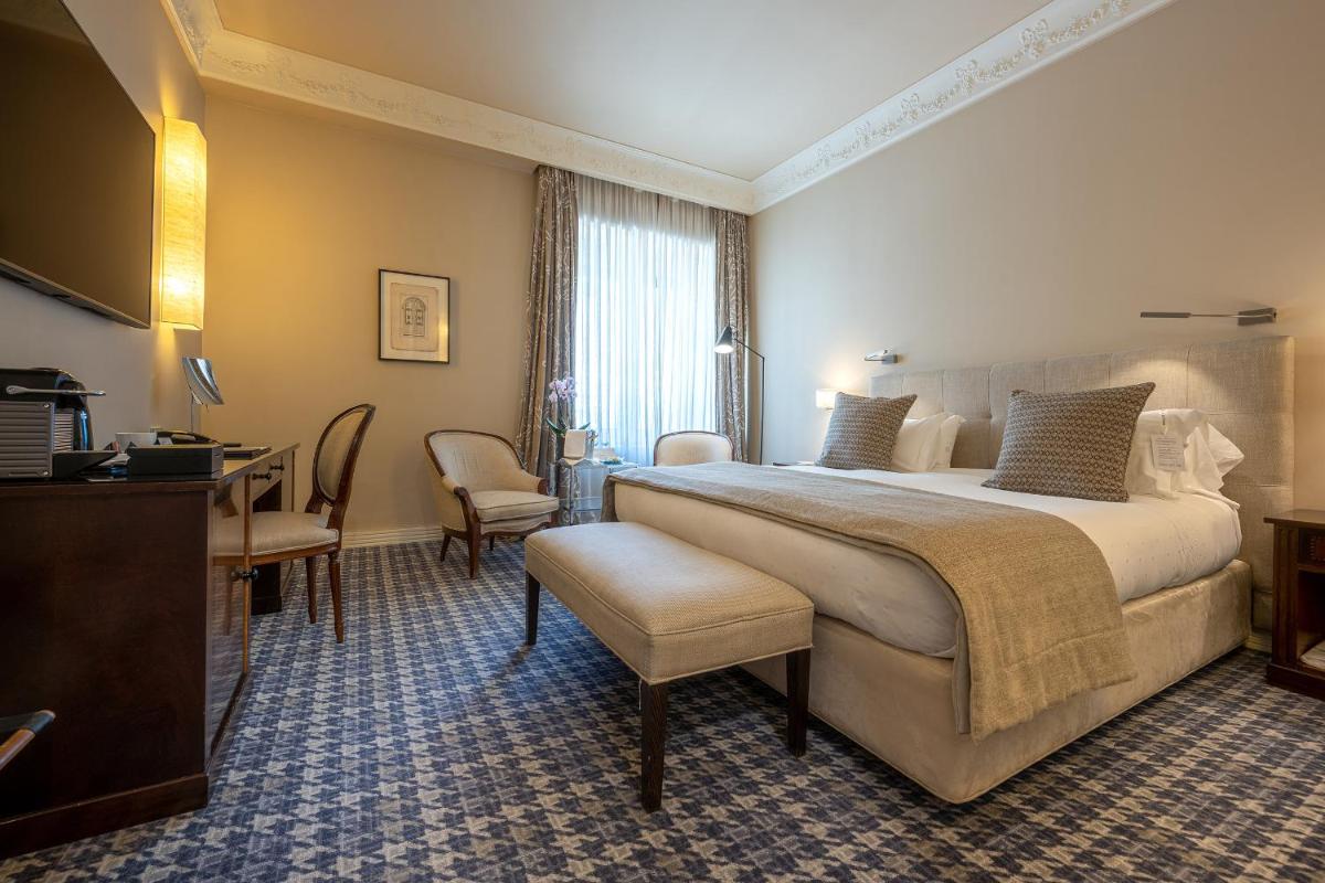 Una habitación de hotel con una cama grande y un escritorio. en Hotel Rector, en Salamanca