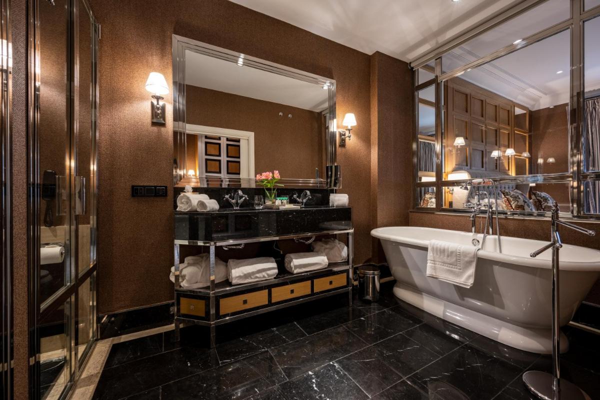 Un baño con bañera y un espejo grande. en Hotel Rector, en Salamanca