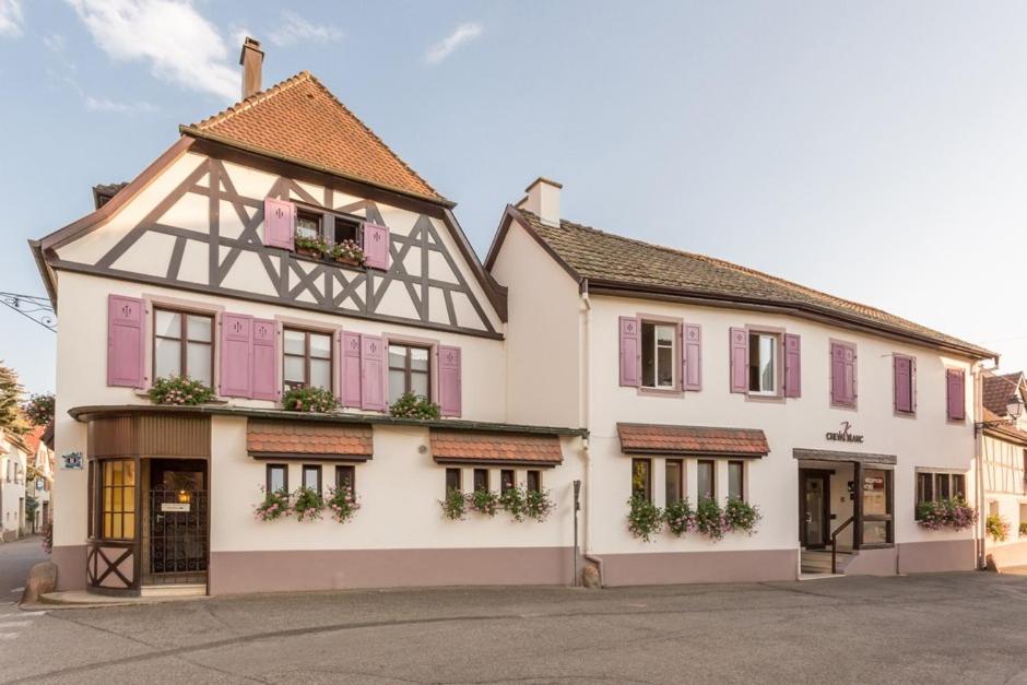 un grand bâtiment blanc avec des fenêtres à volets roses dans l'établissement Auberge du Cheval Blanc depuis 1785, à Westhalten