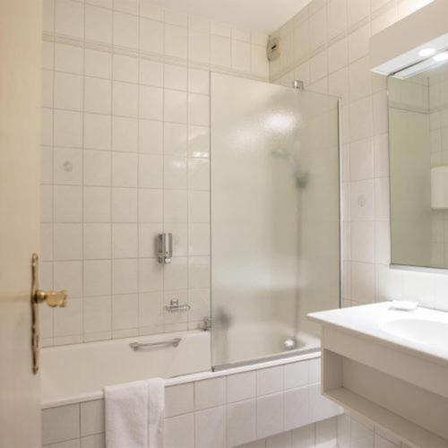 une salle de bain blanche avec une douche et un lavabo dans l'établissement Auberge du Cheval Blanc depuis 1785, à Westhalten