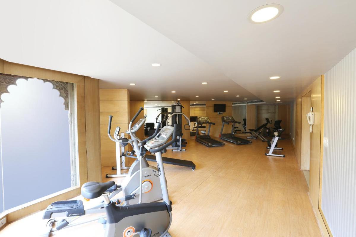 a gym with several tread machines in a room at Golden Tulip Jaipur in Jaipur
