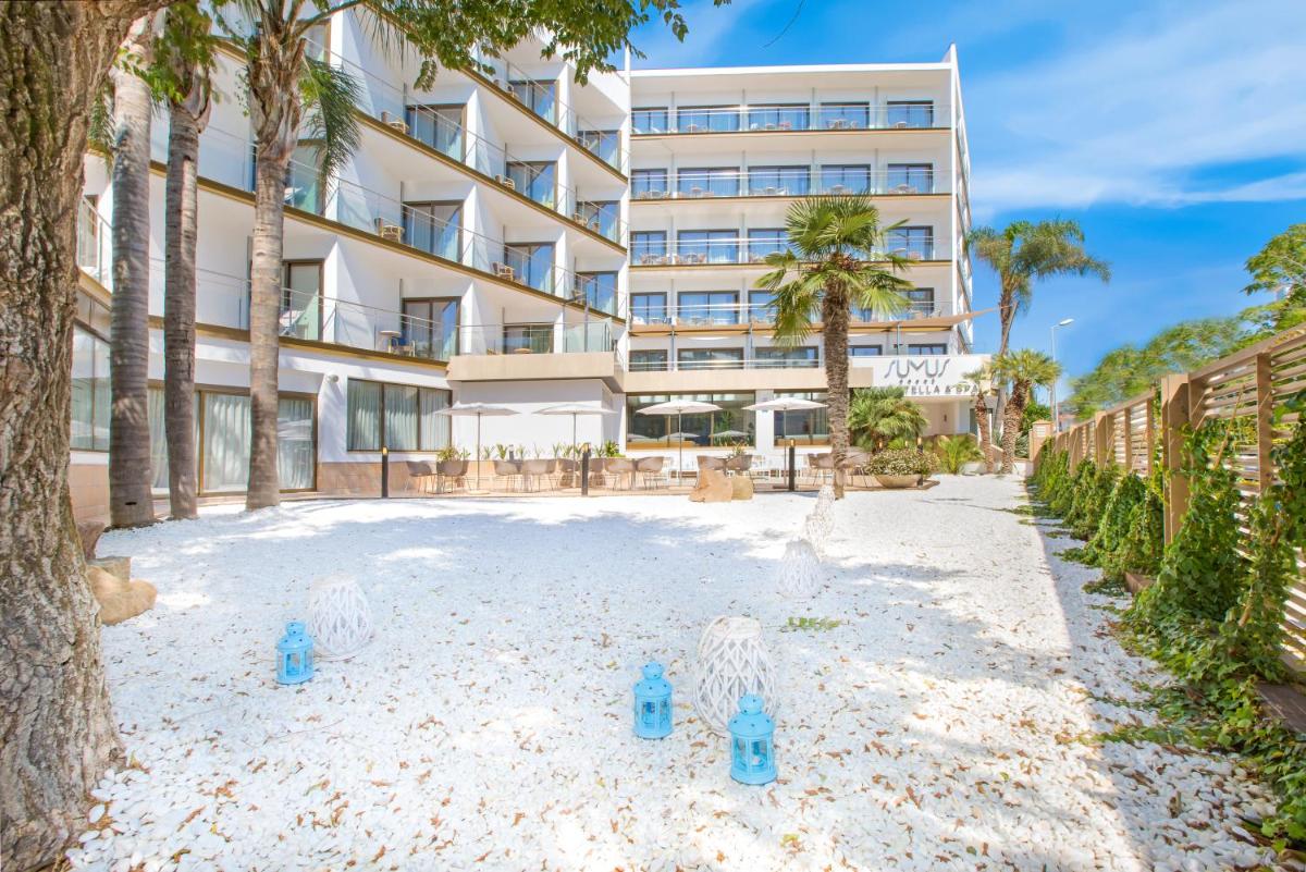 Edificio de aominio con palmeras y contenedores azules en la playa en Sumus Hotel Stella and Spa 4S Adults Recommended, en Pineda de Mar