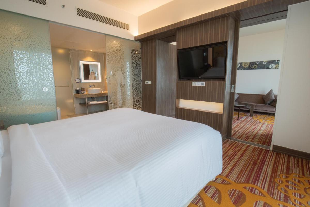 a bedroom with a white bed and a television at Novotel Pune Viman Nagar Road in Pune