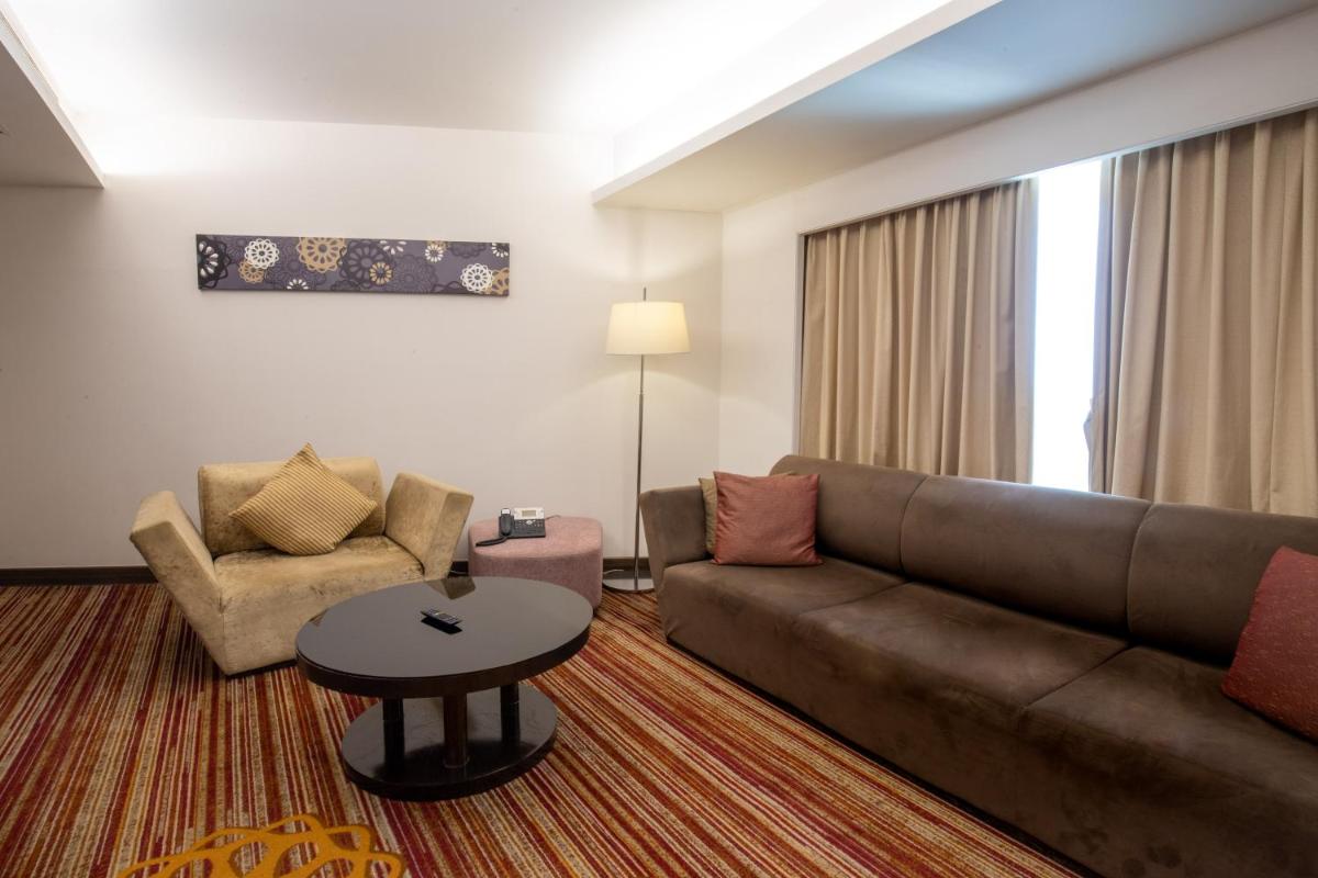 a living room with a couch and a table at Novotel Pune Viman Nagar Road in Pune