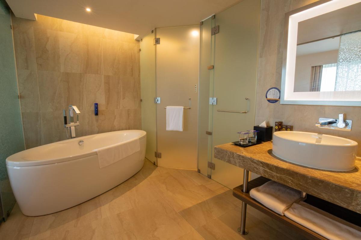 a bathroom with a large tub and a sink at Novotel Pune Viman Nagar Road in Pune