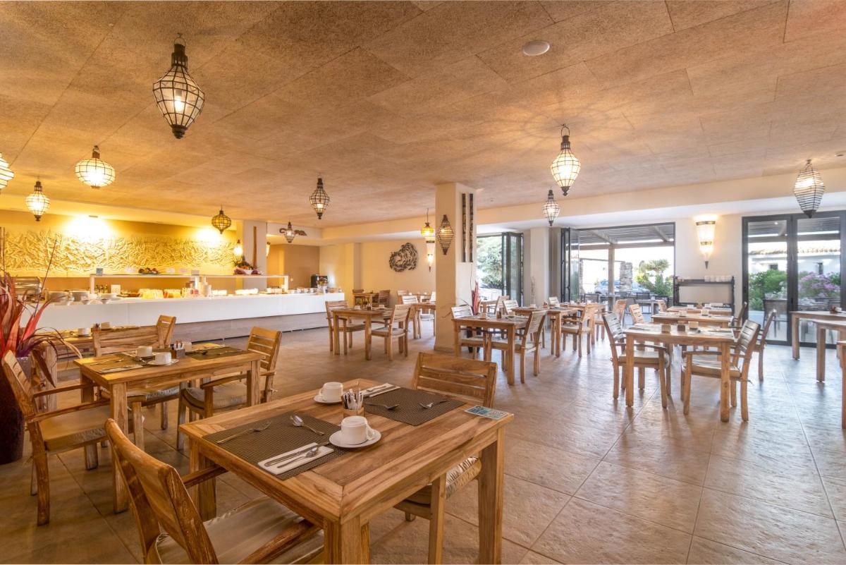 un restaurante con mesas de madera y sillas de madera en El Cortijo de Zahara by QHotels, en Zahara de los Atunes