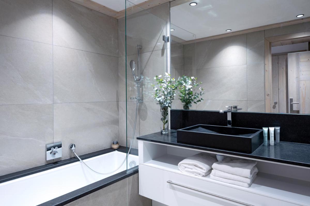 La salle de bains est pourvue d'un lavabo noir et d'une baignoire. dans l'établissement MGM Hôtels & Résidences - Résidence Le Roc Des Tours, au Grand-Bornand