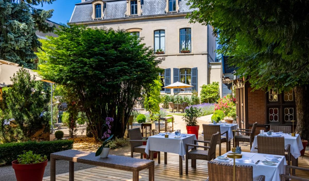 un restaurant avec des tables et des chaises devant un bâtiment dans l'établissement Cèdre Beaune, A Beauvallon Hotel & Spa, à Beaune