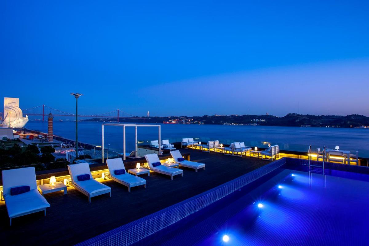 uma piscina com espreguiçadeiras e água à noite em Altis Belem Hotel & Spa, a Member of Design Hotels em Lisboa