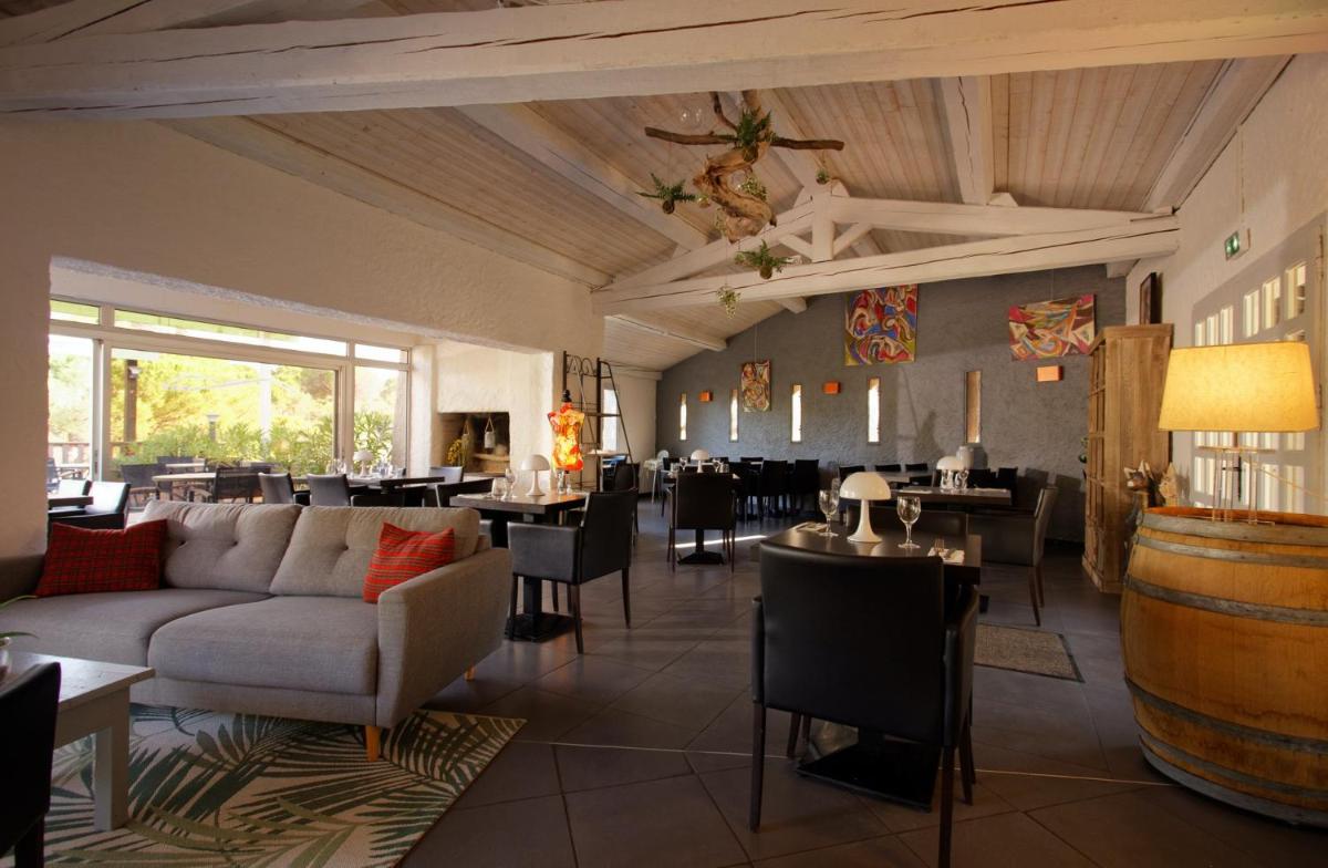 un restaurant avec un canapé, des tables et des chaises dans l'établissement Auberge Val Moureze Hôtel & Spa, à Mourèze