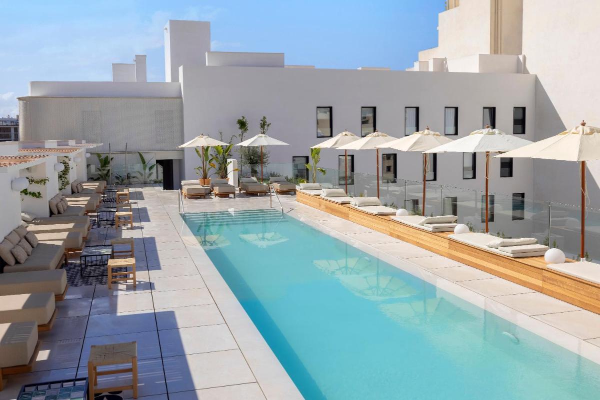 Una imagen de una piscina de hotel con sillas y sombrillas. en HM Palma Blanc, en Palma de Mallorca