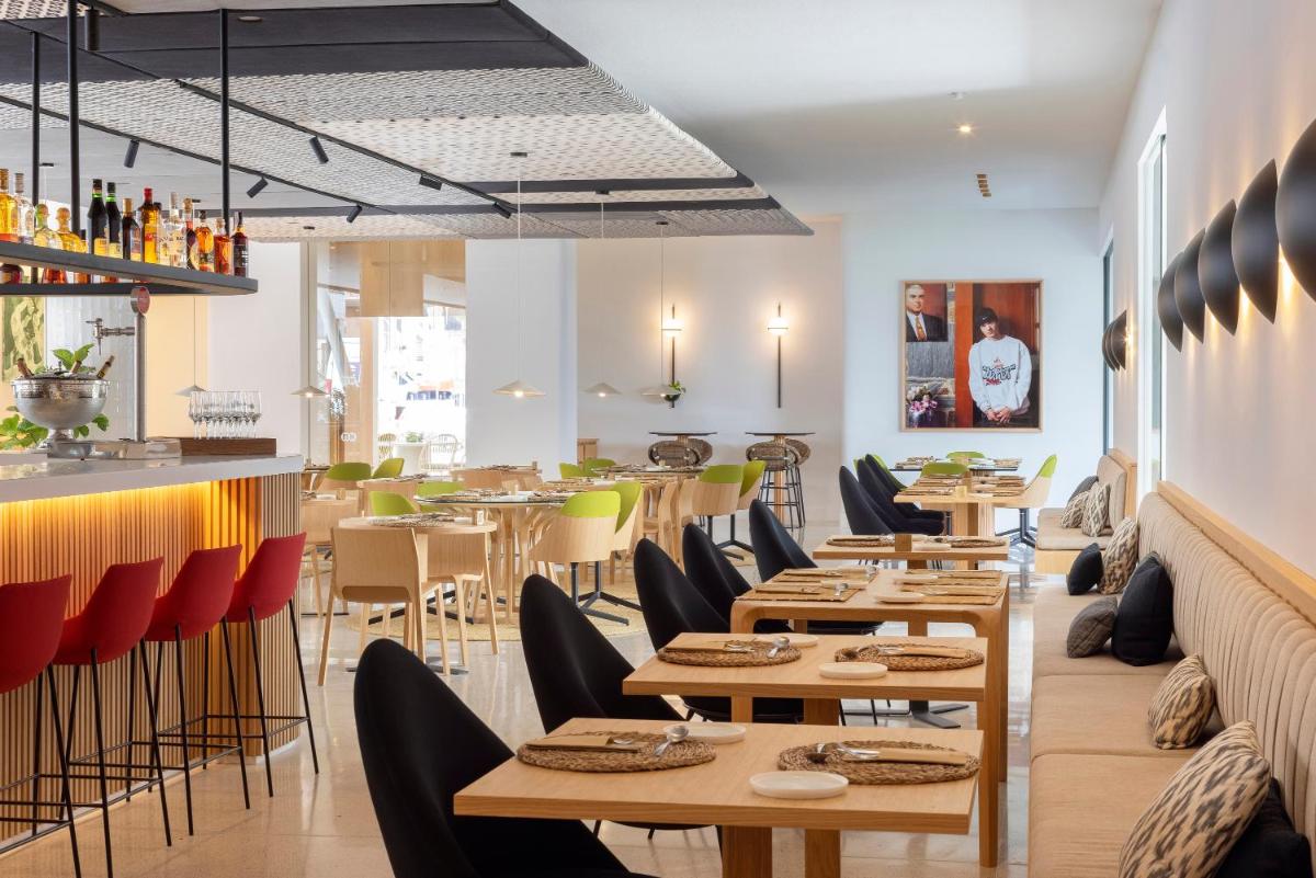 Un restaurante con mesas y sillas de madera y un bar. en HM Palma Blanc, en Palma de Mallorca