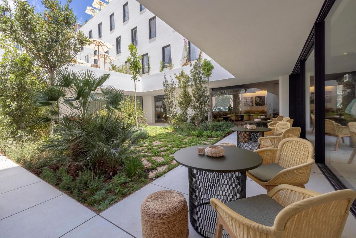 Un patio con sillas y mesas y un edificio. en HM Palma Blanc, en Palma de Mallorca