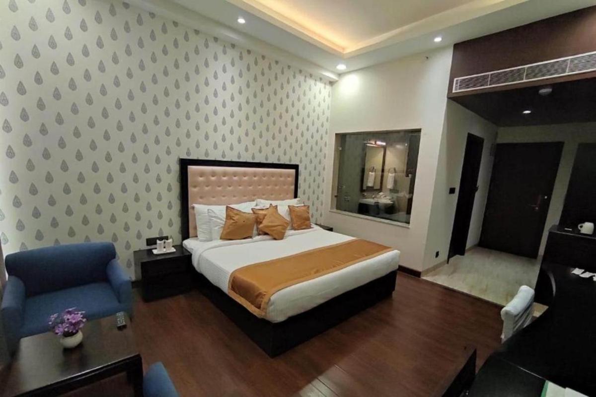 a bedroom with a large bed and a blue chair at The Orchid Shimla in Shimla