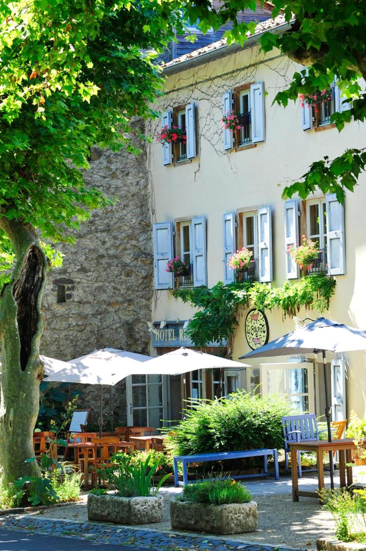 un bâtiment avec des tables et des parasols devant lui dans l'établissement Hotel La Bougnate, à Blesle