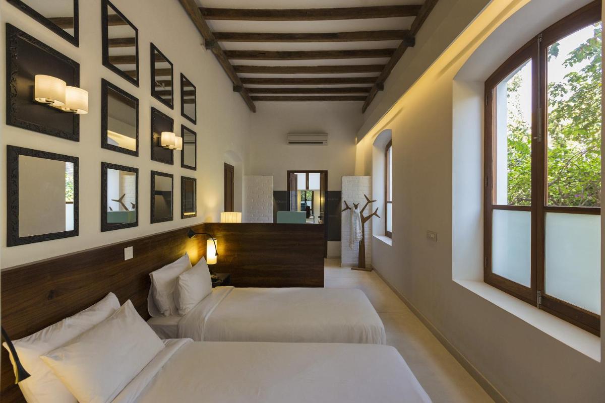 two beds in a room with two windows at La Villa in Puducherry