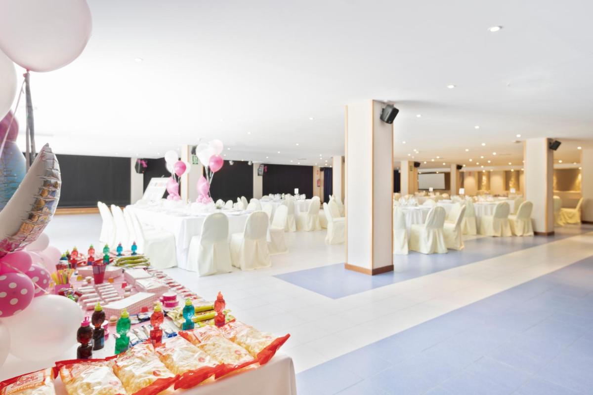 un salón de banquetes con mesas y sillas blancas y globos rosados en Sol Costa Daurada, en Salou 86 fotos más