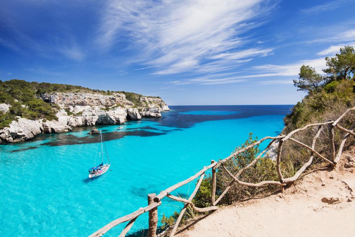 un barco en un río con agua azul en CAP VERMELL GRAND HOTEL, en Canyamel