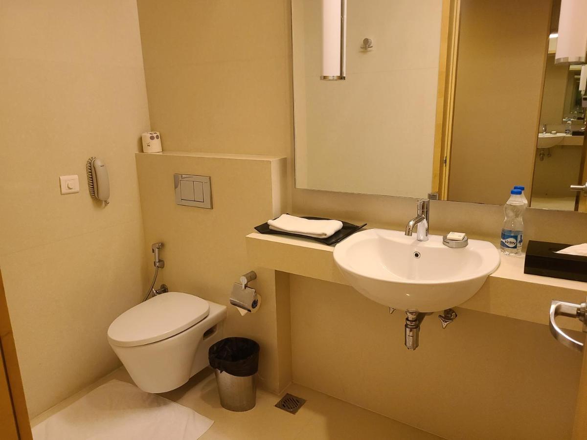 a bathroom with a toilet and a sink at Novotel Hyderabad Airport in Hyderabad