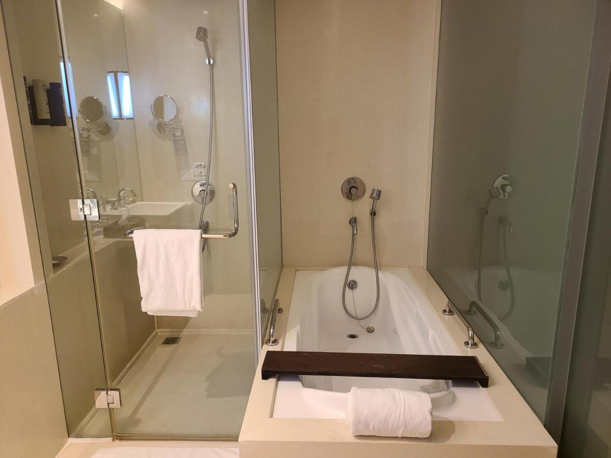 a bathroom with a shower and a bath tub with towels at Novotel Hyderabad Airport in Hyderabad