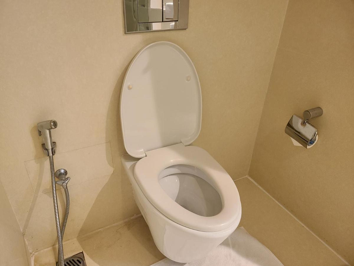 a bathroom with a toilet with a roll of toilet paper at Novotel Hyderabad Airport in Hyderabad