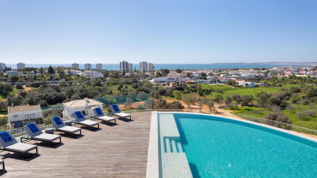 uma piscina com espreguiçadeiras em um deck de madeira em Longevity Health & Wellness Hotel - Adults Only em Alvor