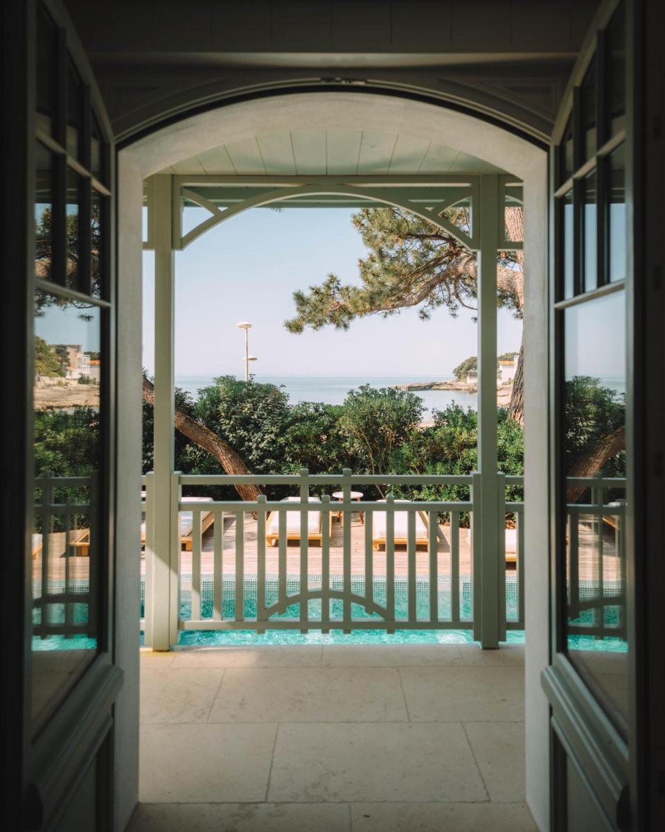 une porte ouverte s'ouvrant sur un balcon avec vue sur l'océan. dans l'établissement Hôtel Hemen, à Saint-Palais-sur-Mer 19 autres photos